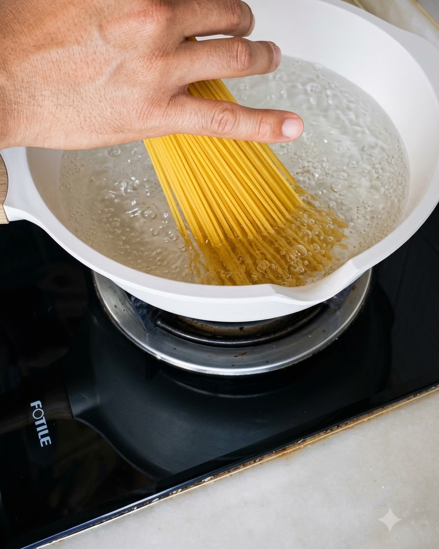 A handful of dry spaghetti noodles being lowered into a white pot filled with bubbling boiling water.
