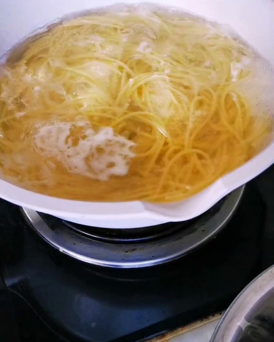 Spaghetti noodles actively boiling in a pot of hot water.