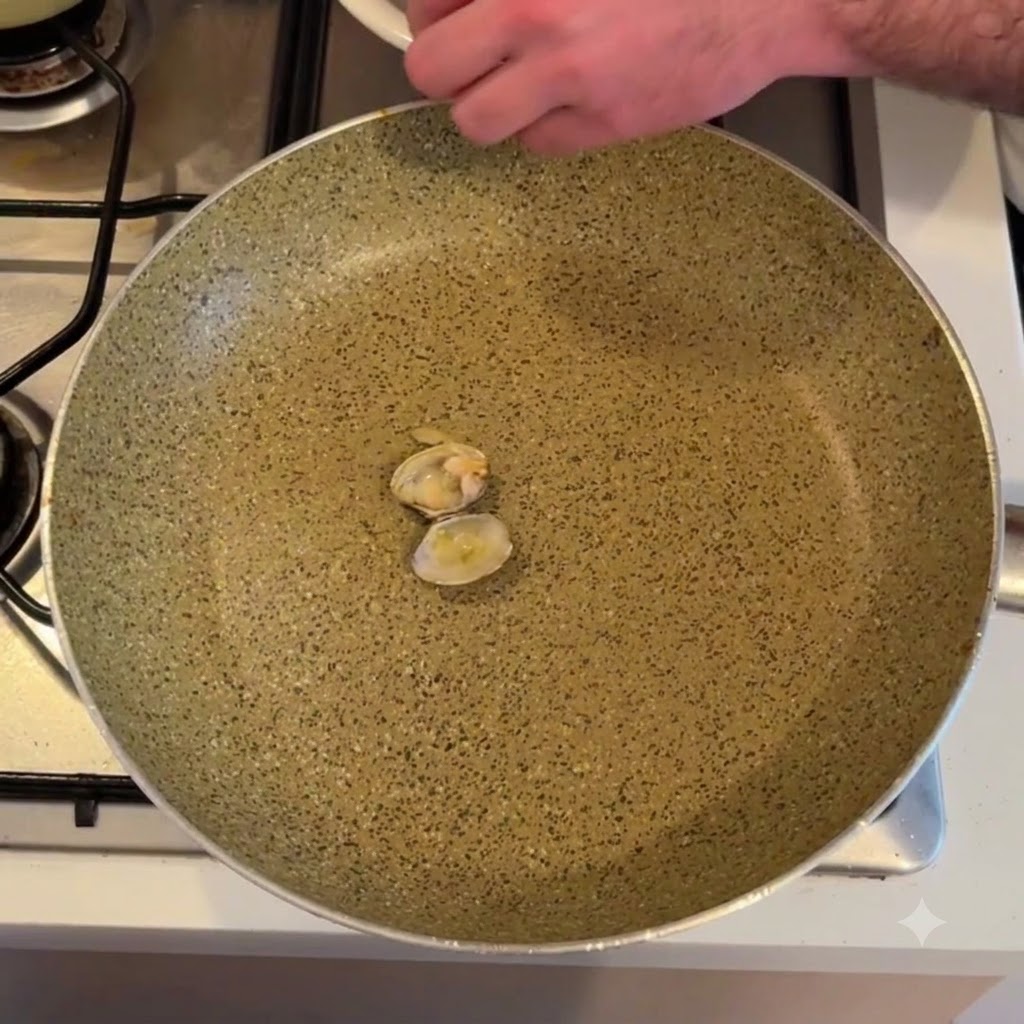 Clam meat being shelled above an empty frying pan.