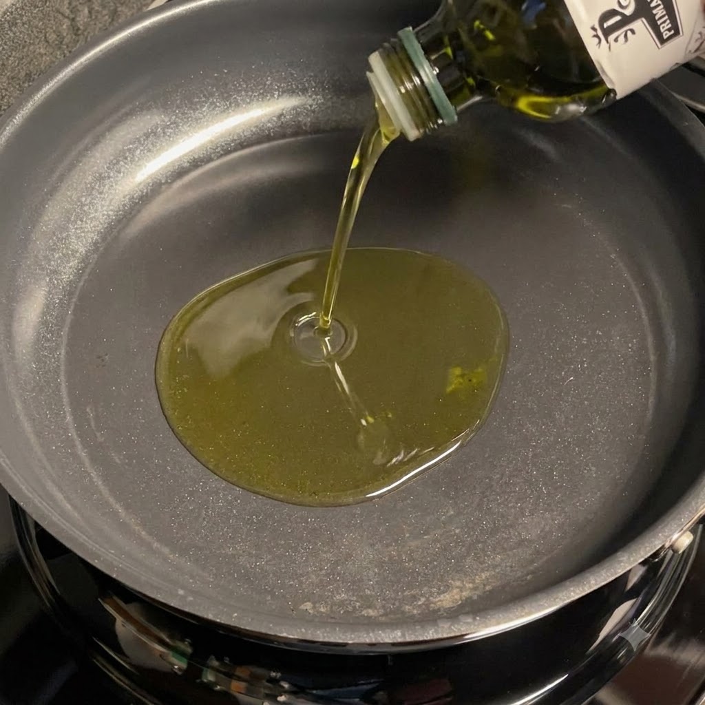 Olive oil being poured into a pan to fry sliced garlic.