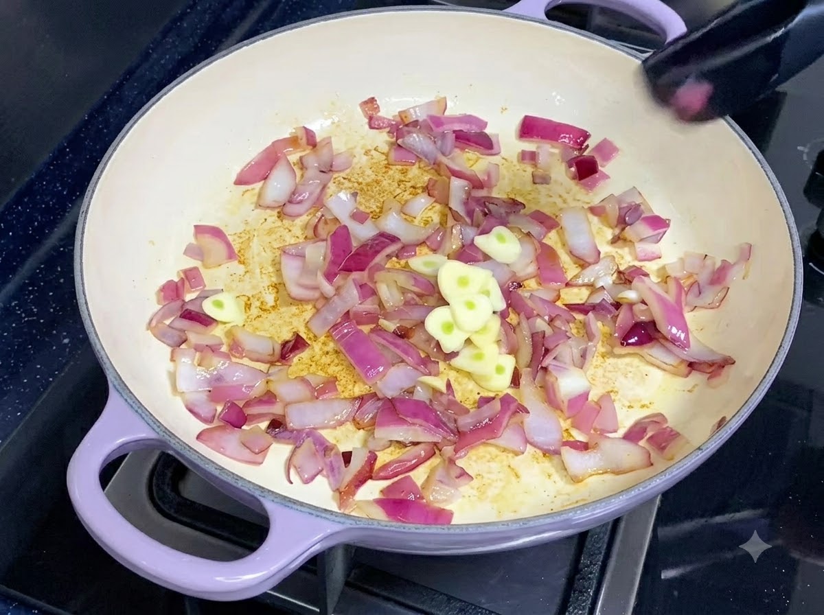 Freshly sliced garlic pieces being added to a pan of sautéed red onions.