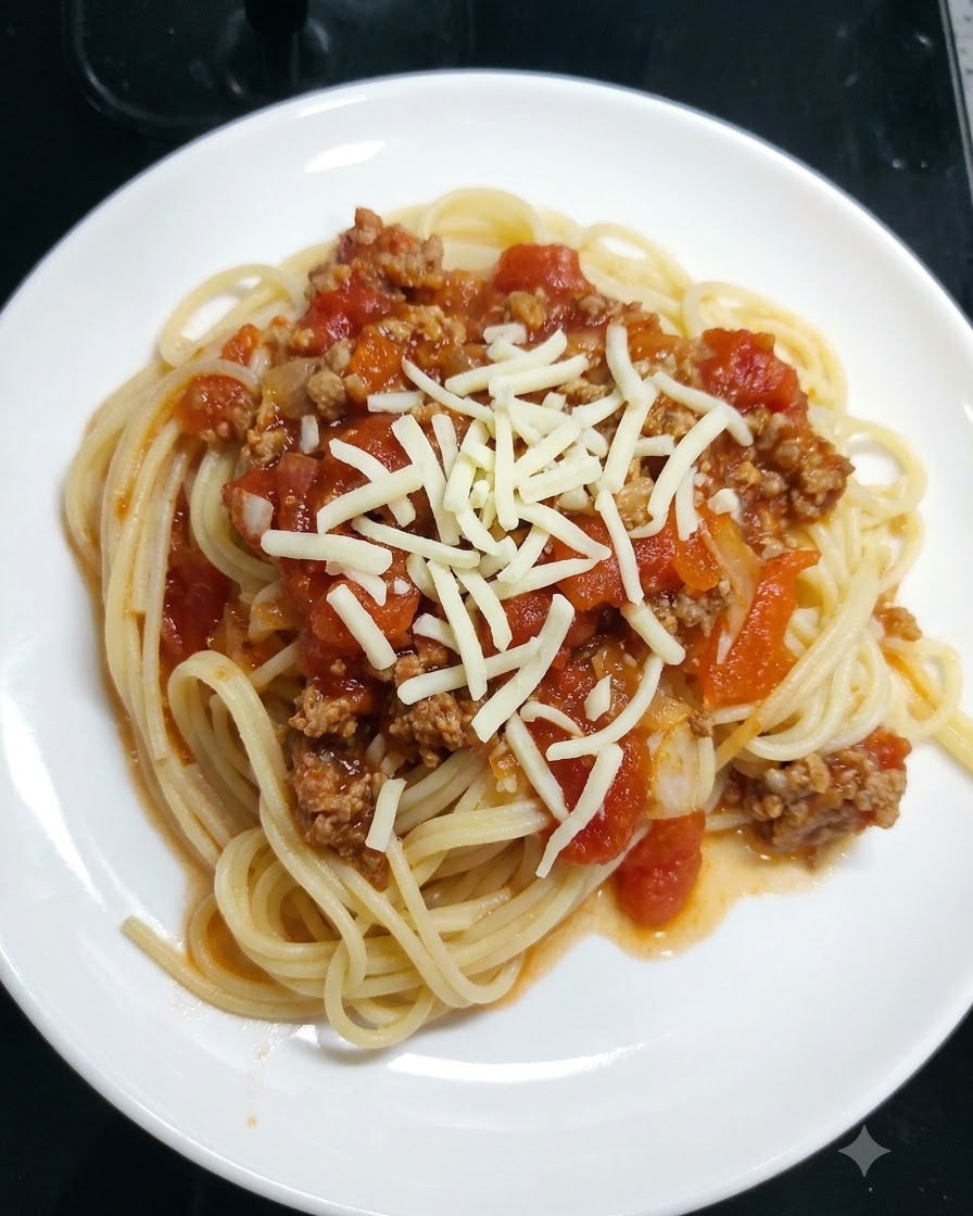 Shredded mozzarella cheese being sprinkled over spaghetti covered in tomato sauce on a white plate.