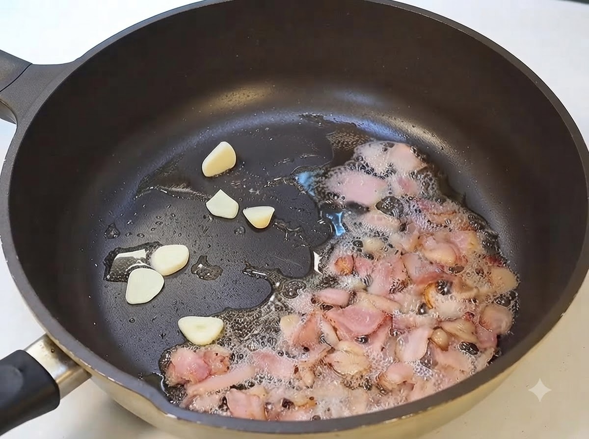 Garlic slices and bacon frying together in a pan.