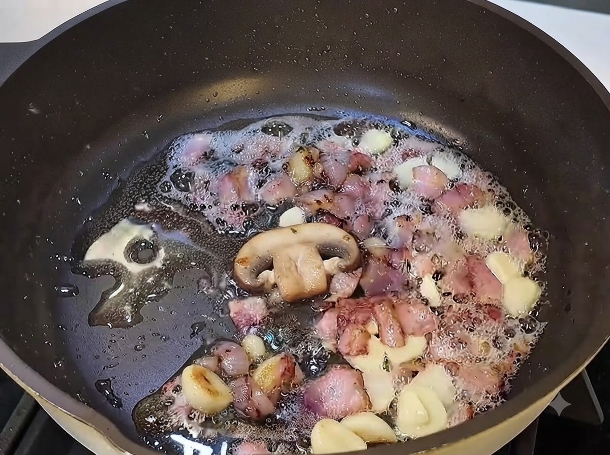 Sliced mushrooms cooking in the pan with bacon and garlic.
