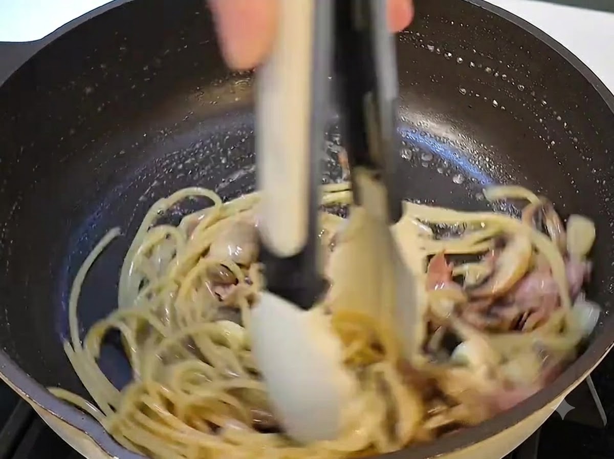 A close-up view of butter being added and melting into the pasta mixture in the pan.