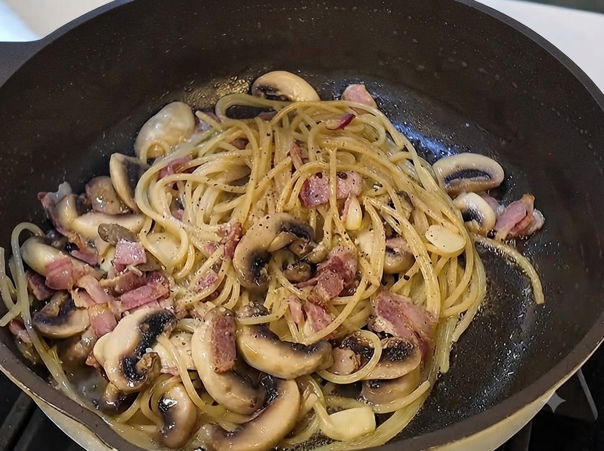 Black truffle sauce and freshly ground black pepper being incorporated into the pasta pan.