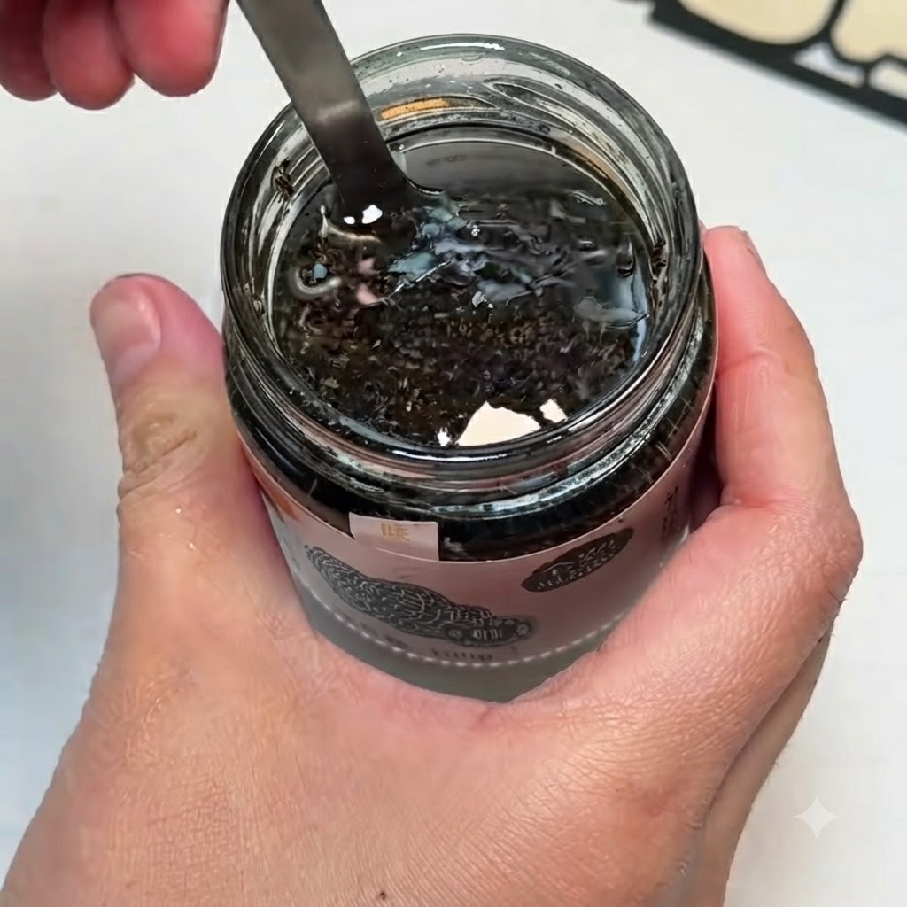 A small bowl containing black truffle sauce, egg yolks, and salt being mixed together with a spoon.