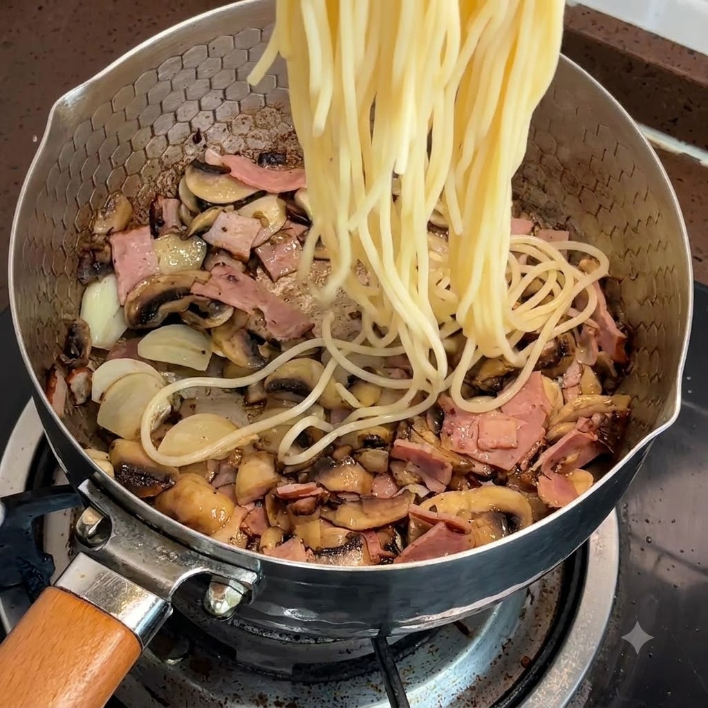 Cooked spaghetti noodles being added to the pan with bacon and mushrooms.