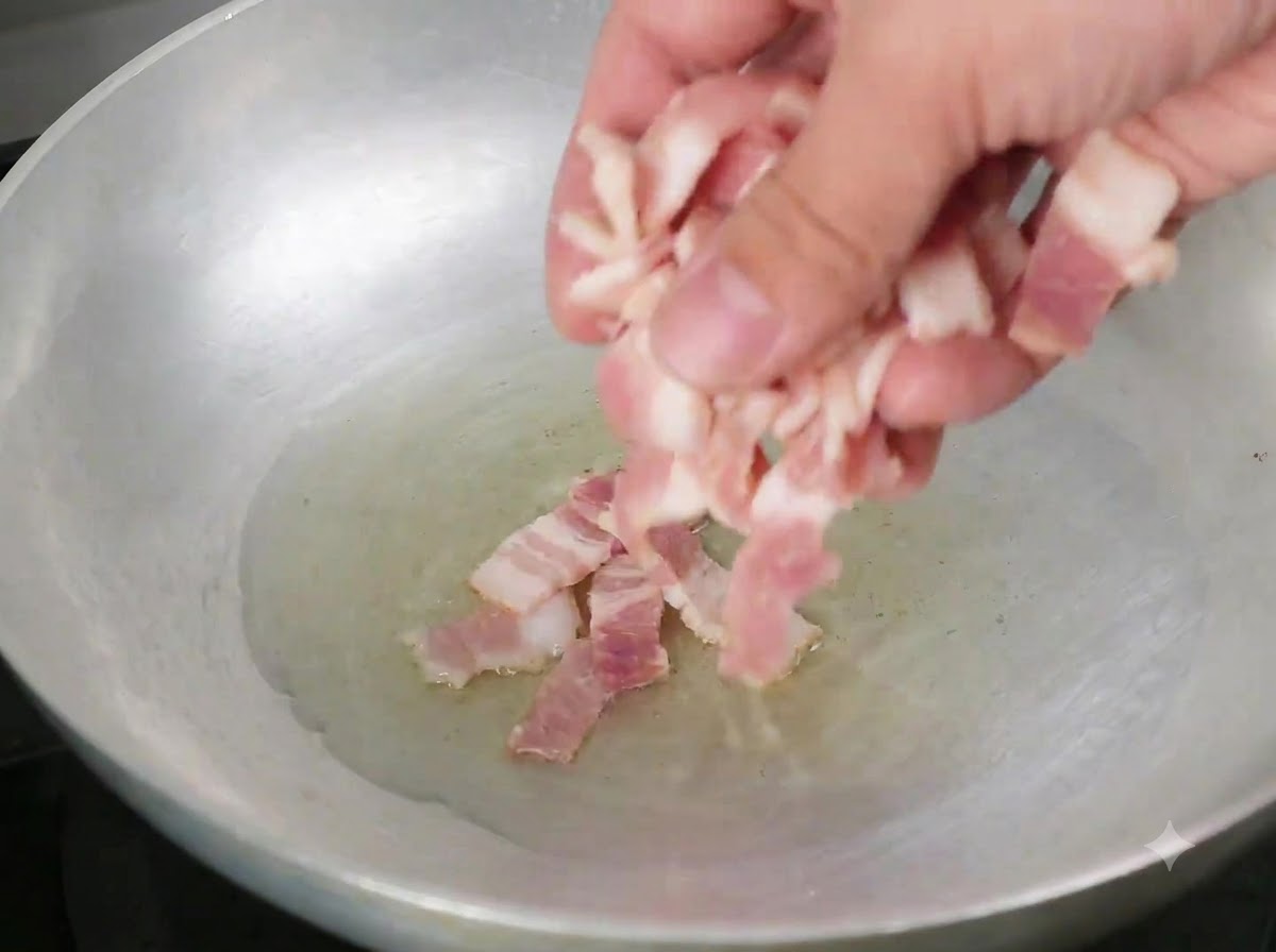 Bacon pieces being dropped into a pan with hot olive oil.