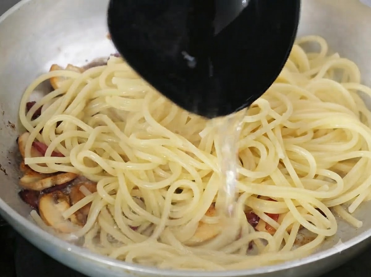 Ladle pouring starchy pasta water into the pan containing pasta and ingredients.
