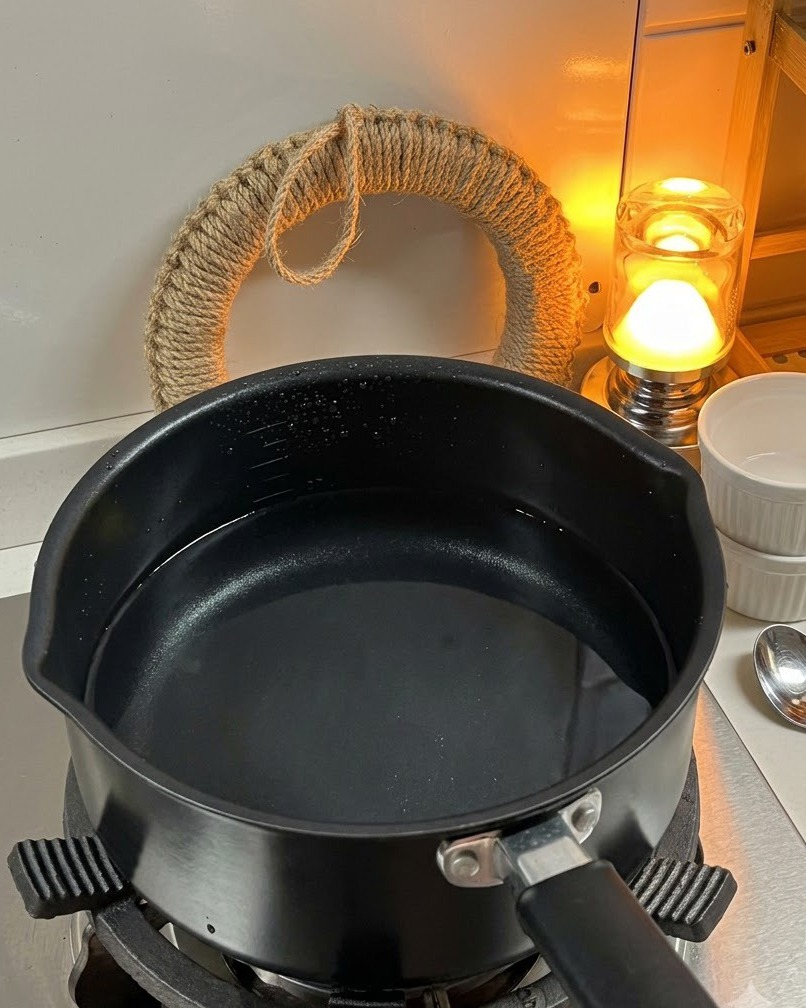 Dry fusilli pasta being added to a pot of boiling water on the stove.