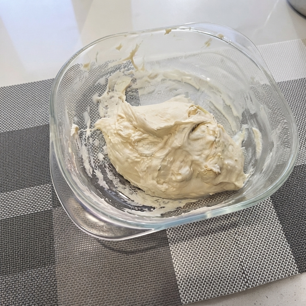 Rough pizza dough mixture gathered in a clear glass bowl.