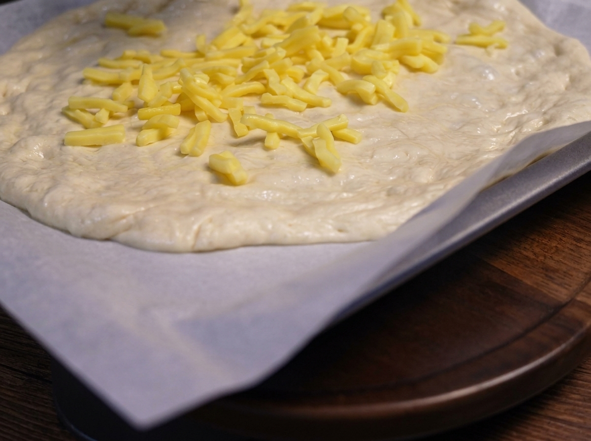 Sautéed sliced mushrooms placed on top of the cheese layer on the pizza dough.
