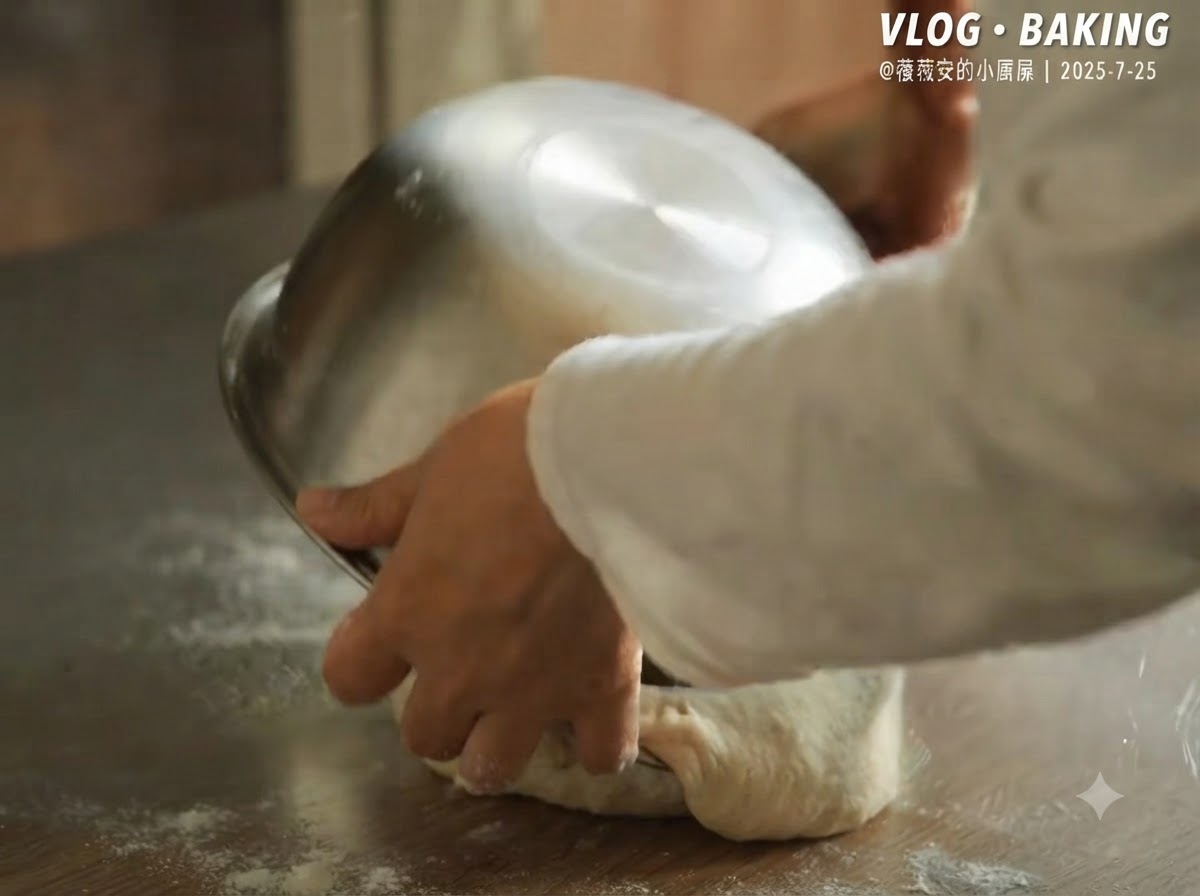 A metal bowl being flipped over to release fermented pizza dough onto a floured countertop.