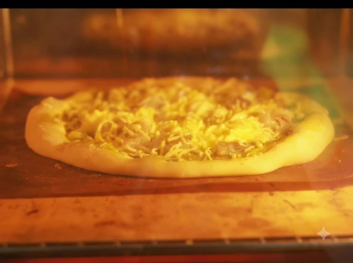 A pizza baking on a tray inside a lit oven with glowing heating elements.