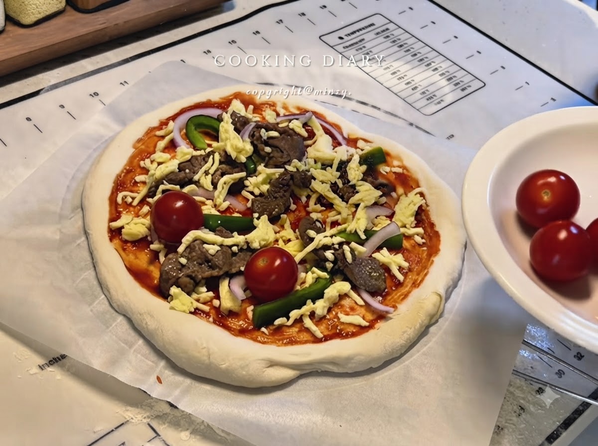 A fully assembled pizza with cheese, beef, peppers, onions, and whole cherry tomatoes on parchment paper.