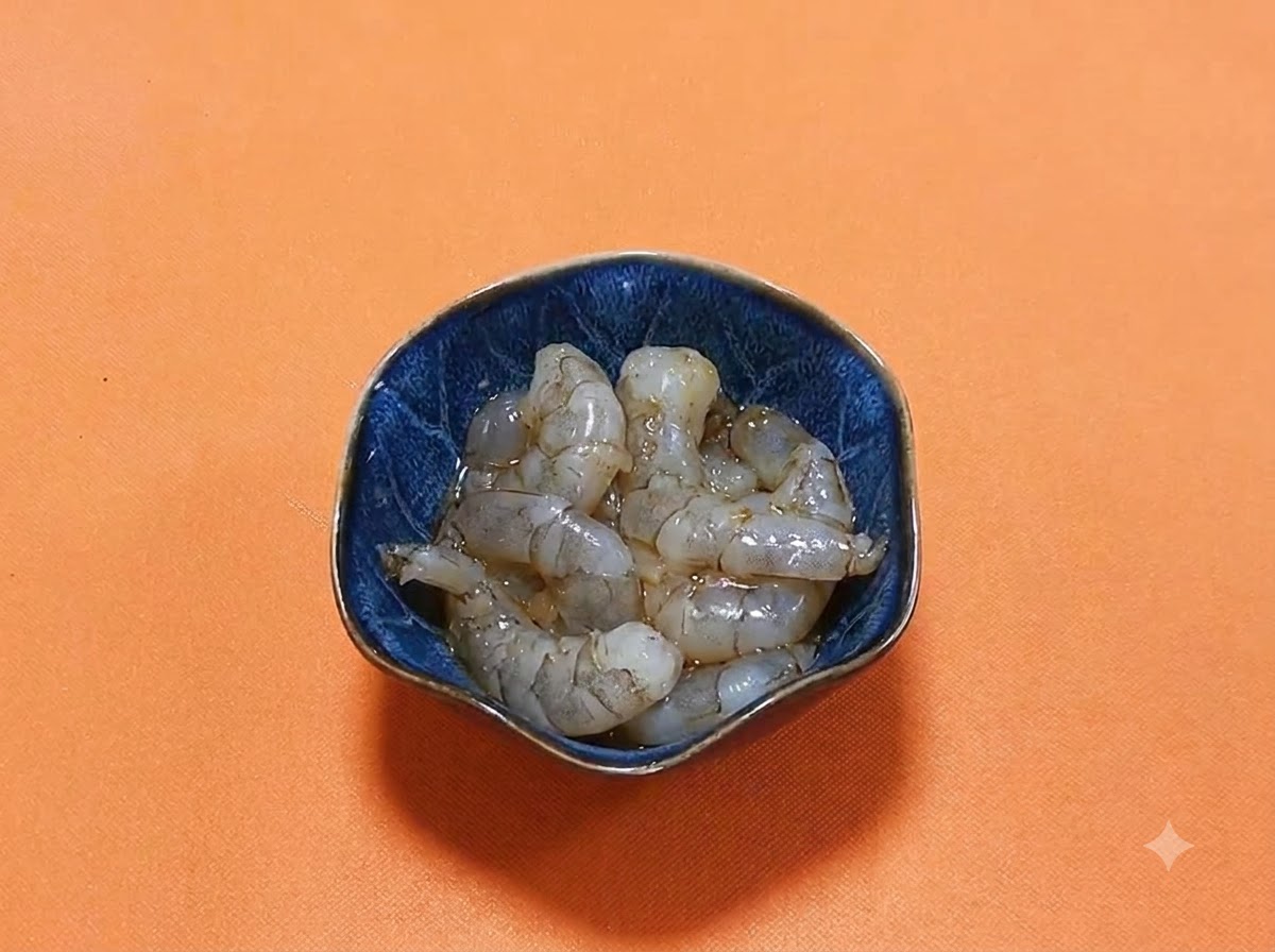 Peeled raw shrimp resting in a dark blue bowl with a glossy marinade of dark soy sauce and spices.
