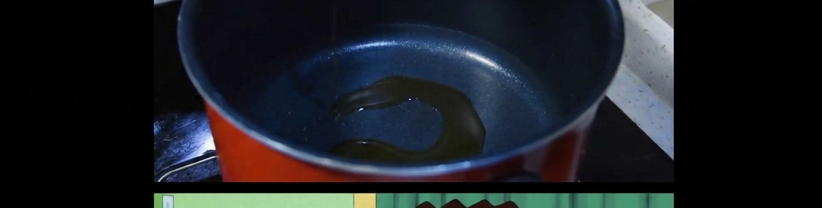 A thin layer of sesame oil being heated at the bottom of a dark cooking pot.