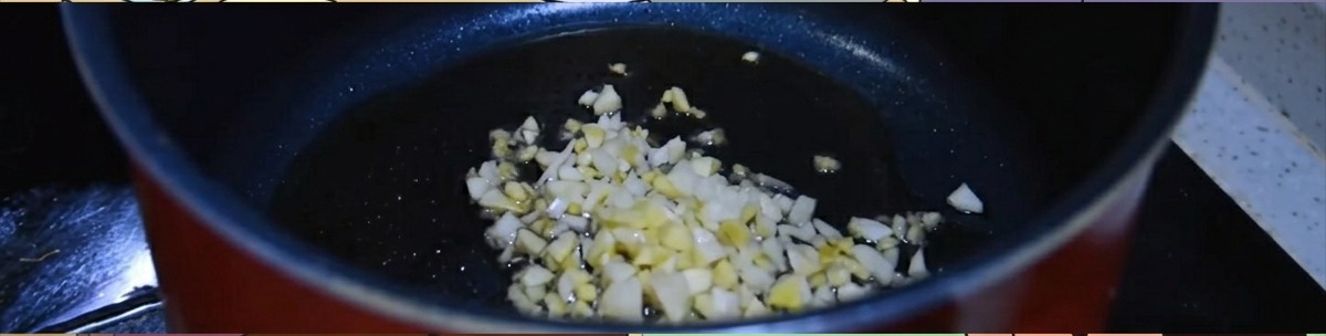 Minced ginger and garlic sizzling in a dark pot with hot sesame oil.
