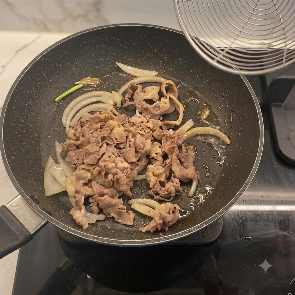 Blanched beef slices mixed with onions in a frying pan.