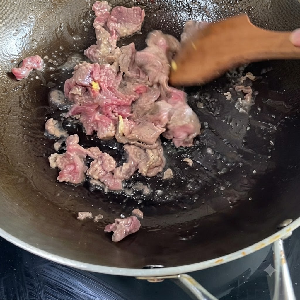 Marinated beef sizzling and being stir-fried in a hot wok using a wooden spatula.
