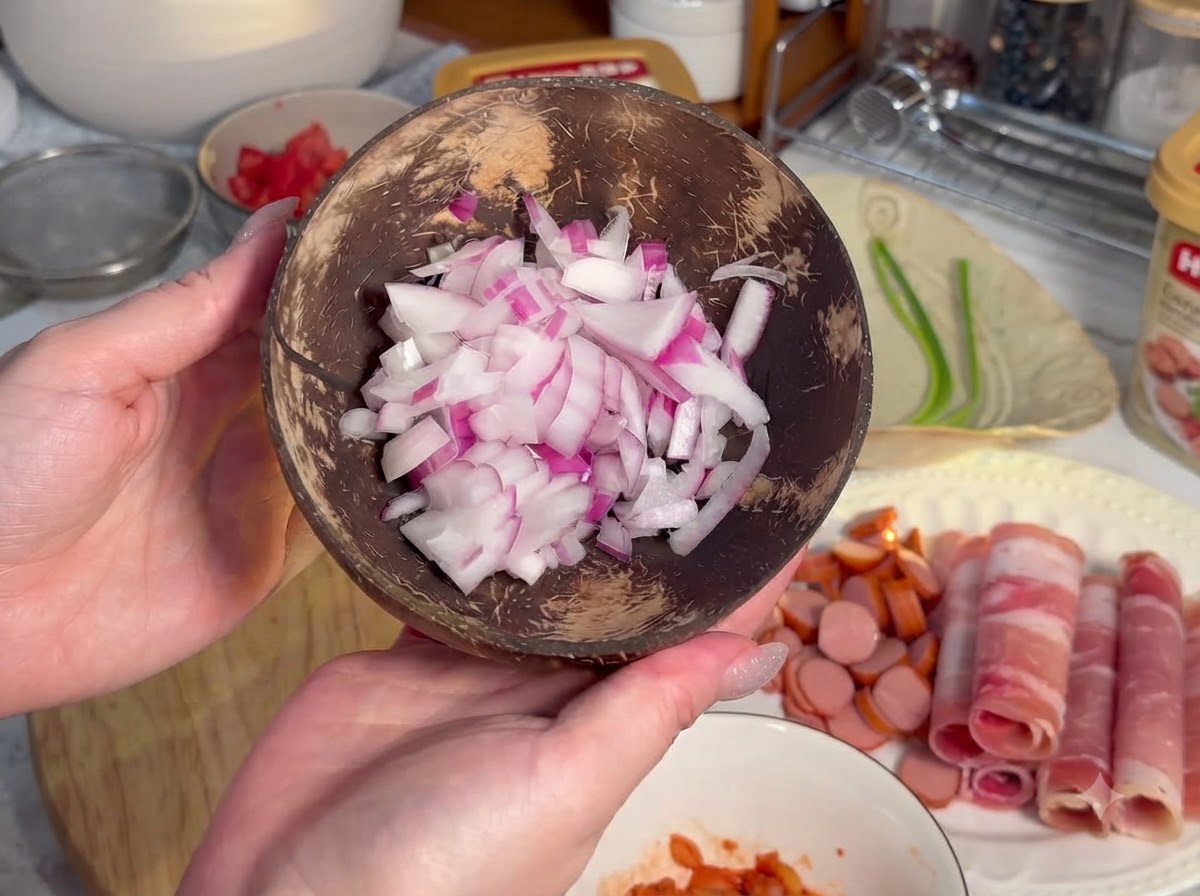 Sausages cut into small circular rounds arranged on a wooden board next to rolled meat.