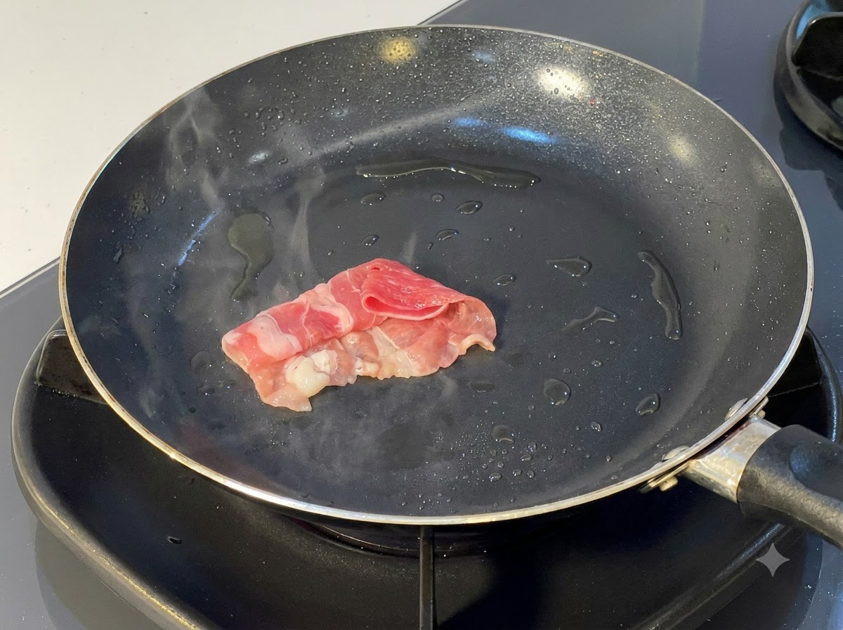 Rolled beef slices being placed and seared in a hot oiled frying pan.