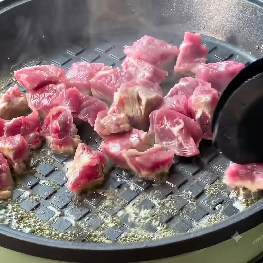 Beef cubes cooking and browning in a hot pan.