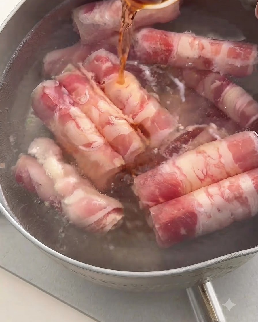 Dark cooking wine being poured from a spoon into a pot of boiling water containing beef rolls.