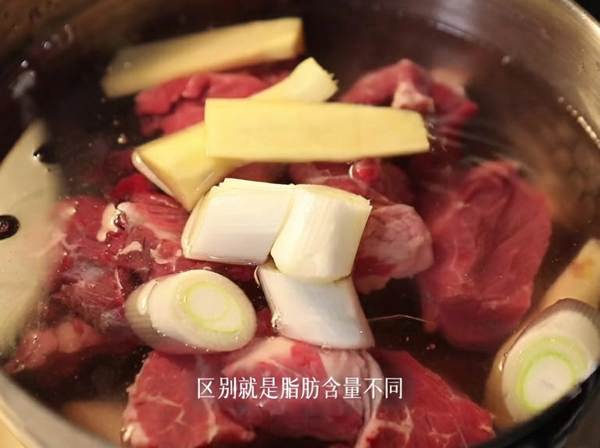 Raw beef brisket pieces submerged in a pot of cold water with sliced ginger and scallions.