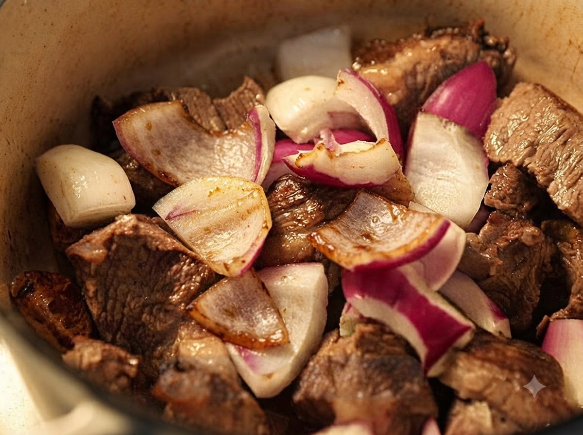 Chopped red onions mixed with browned beef in the cooking pot.