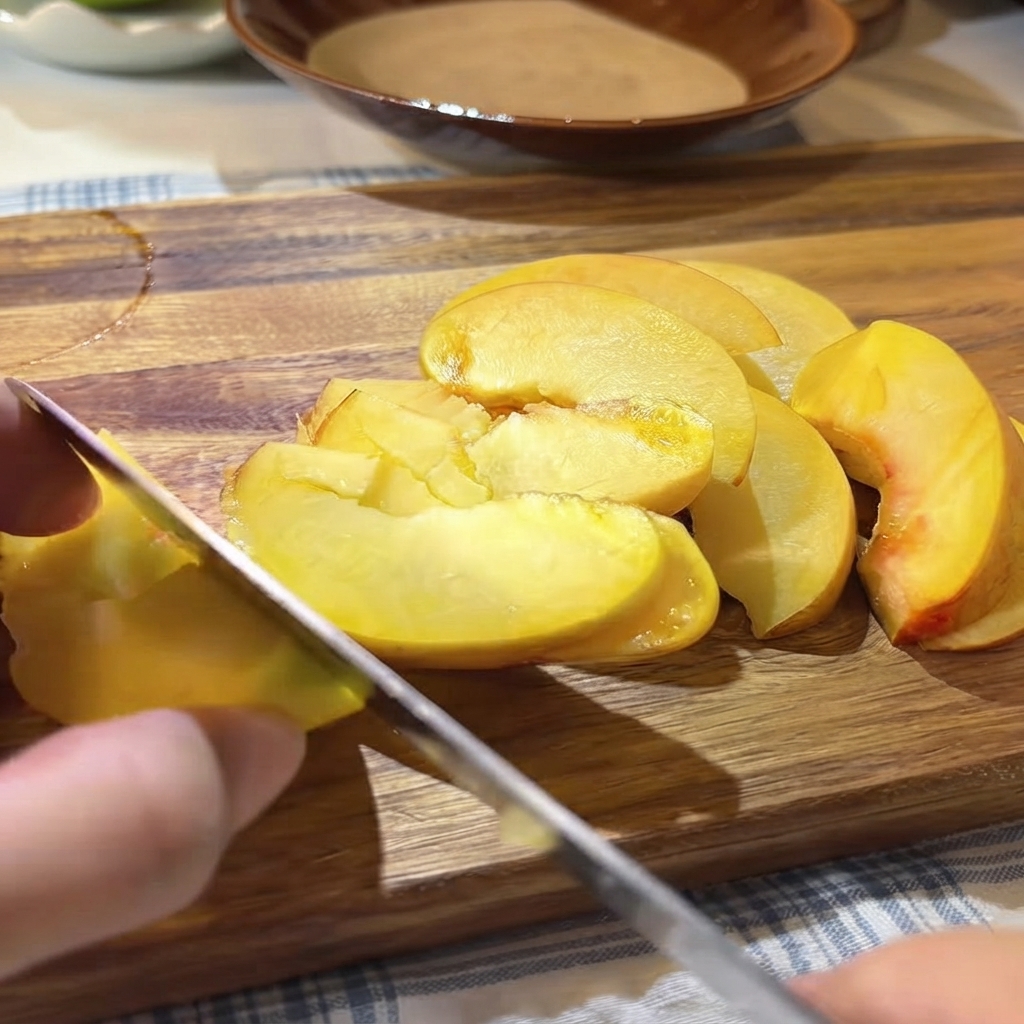 Fresh passionfruit seeds and pulp being spooned over the sliced yellow peaches on the cutting board.