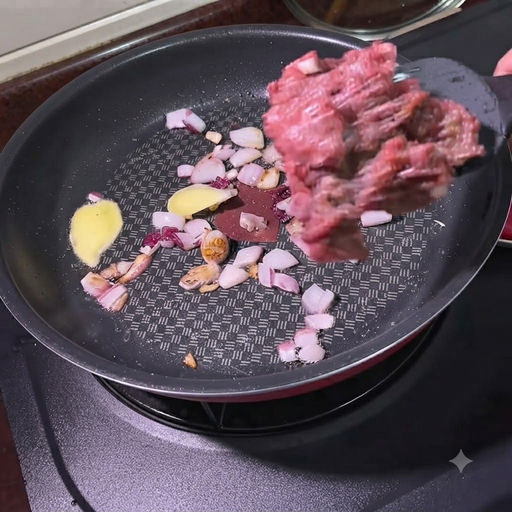 Ground beef being added with a spatula into a pan containing sautéed onions and ginger slices.