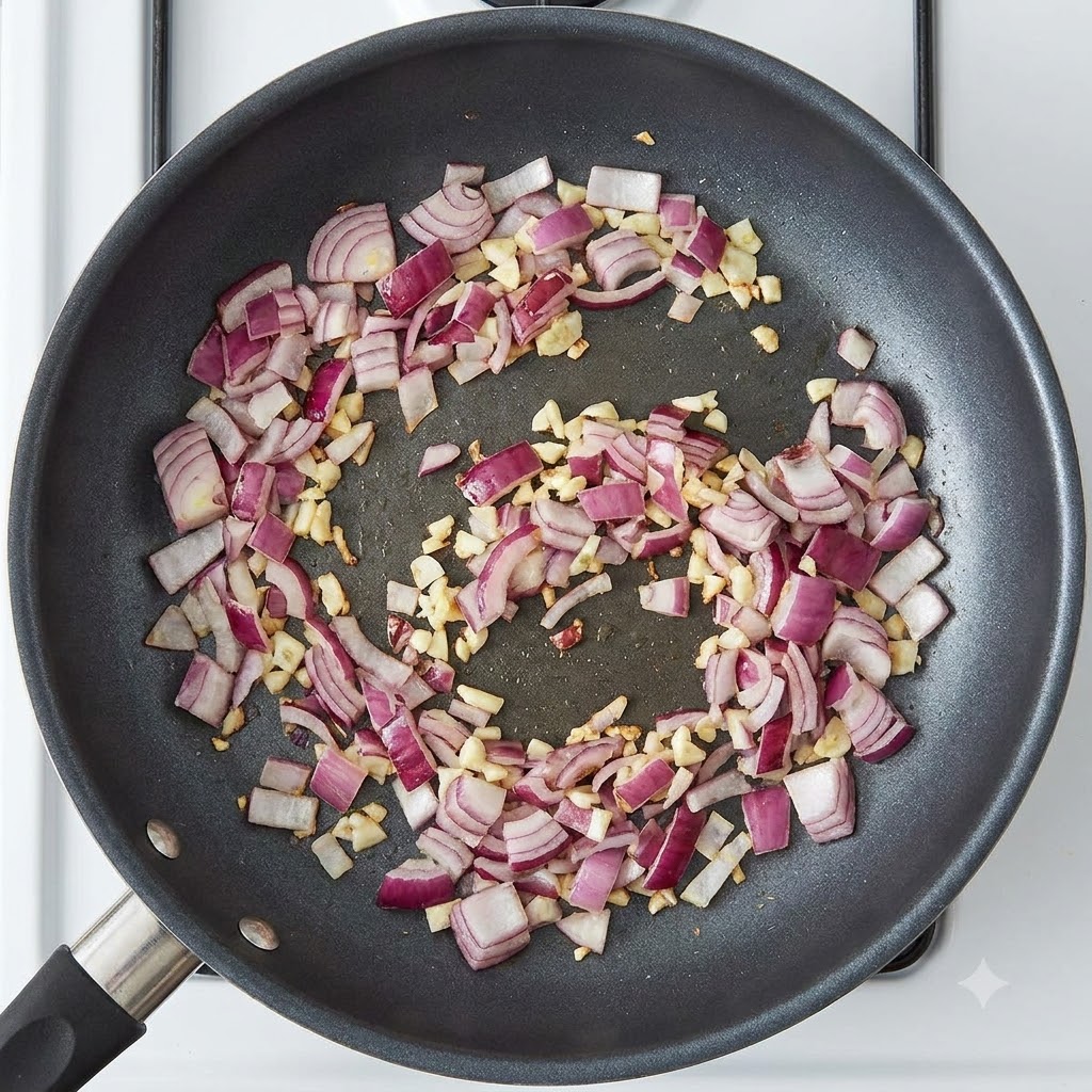 Curry paste blocks sitting in the pan with sautéed red onions and garlic.