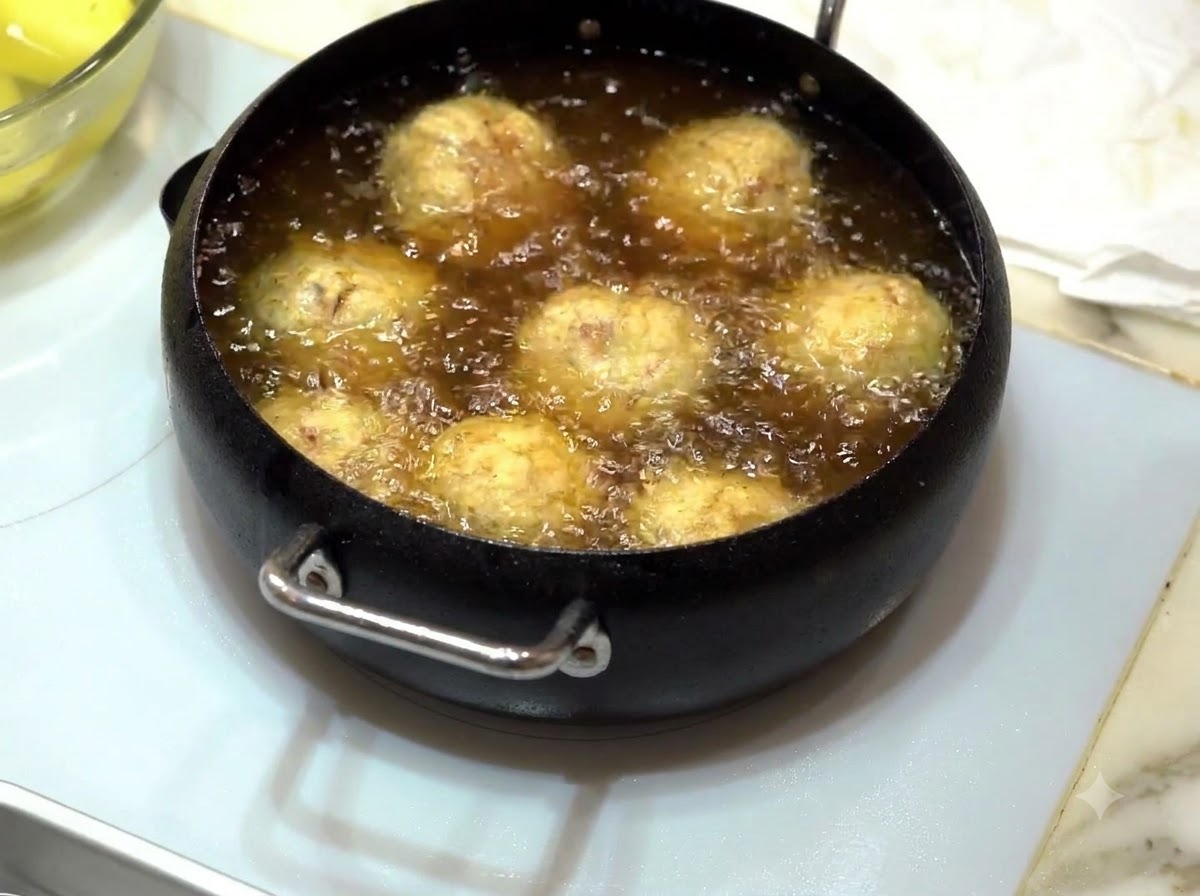 Meatballs frying in bubbling hot oil until golden brown.