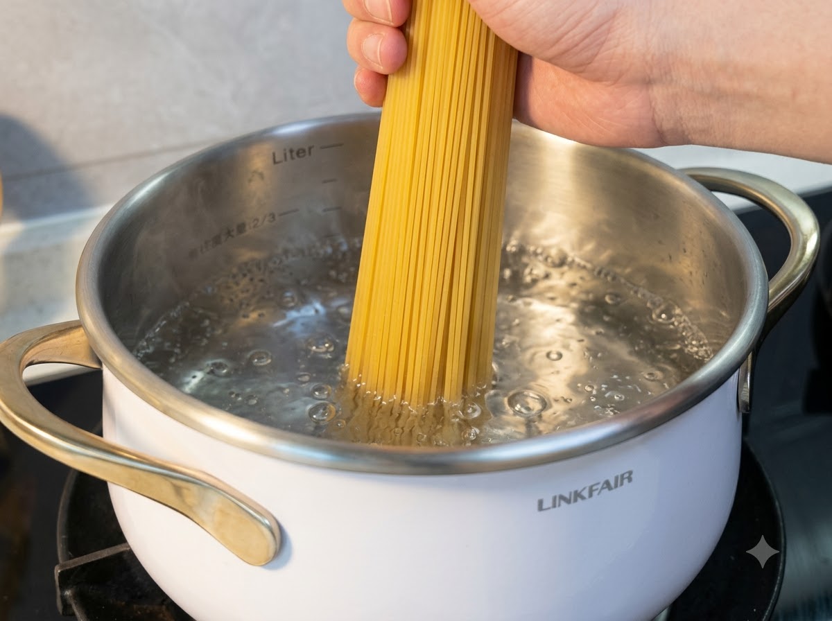 A hand holding dry rice noodles as they are submerged into a pot of boiling water.