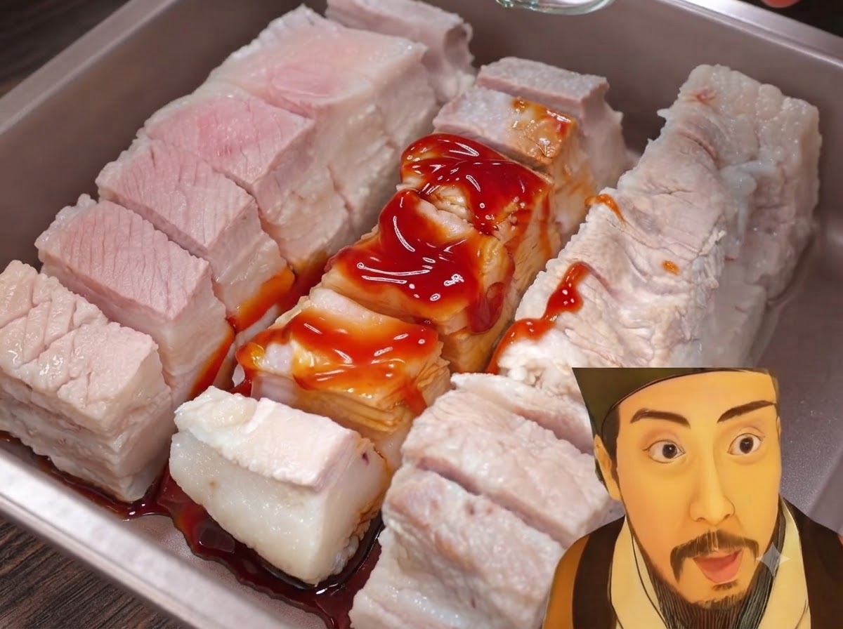 Seasoning powder being sprinkled over marinated pork belly pieces in a tray.
