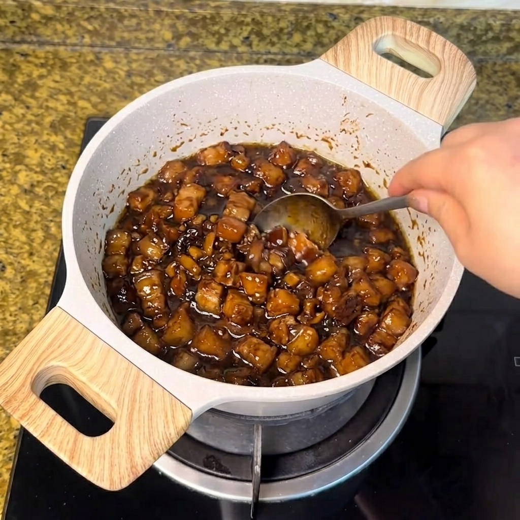 White sugar being stirred with a spoon into the simmering dark meat sauce.