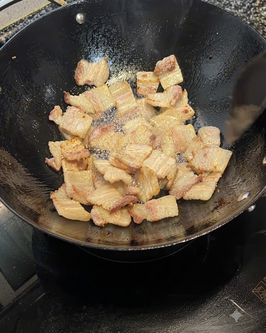 Pork belly slices frying in a wok, releasing fat and turning golden brown.
