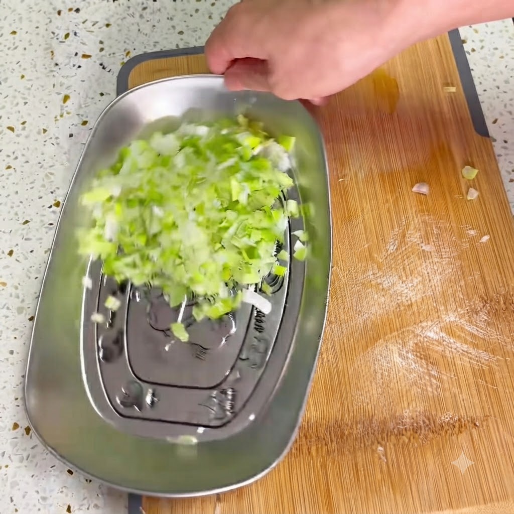 Preserved mustard greens being finely minced with a sharp cleaver on a wooden board.