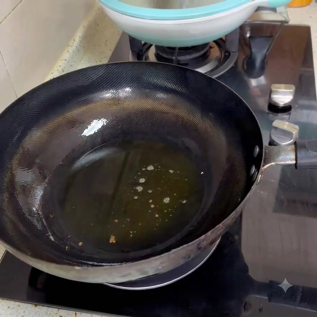 Two spoonfuls of spicy bean paste frying in hot oil inside a black wok.