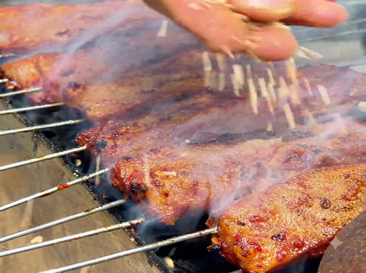 White sesame seeds falling onto glistening cooked ribs on a grill.