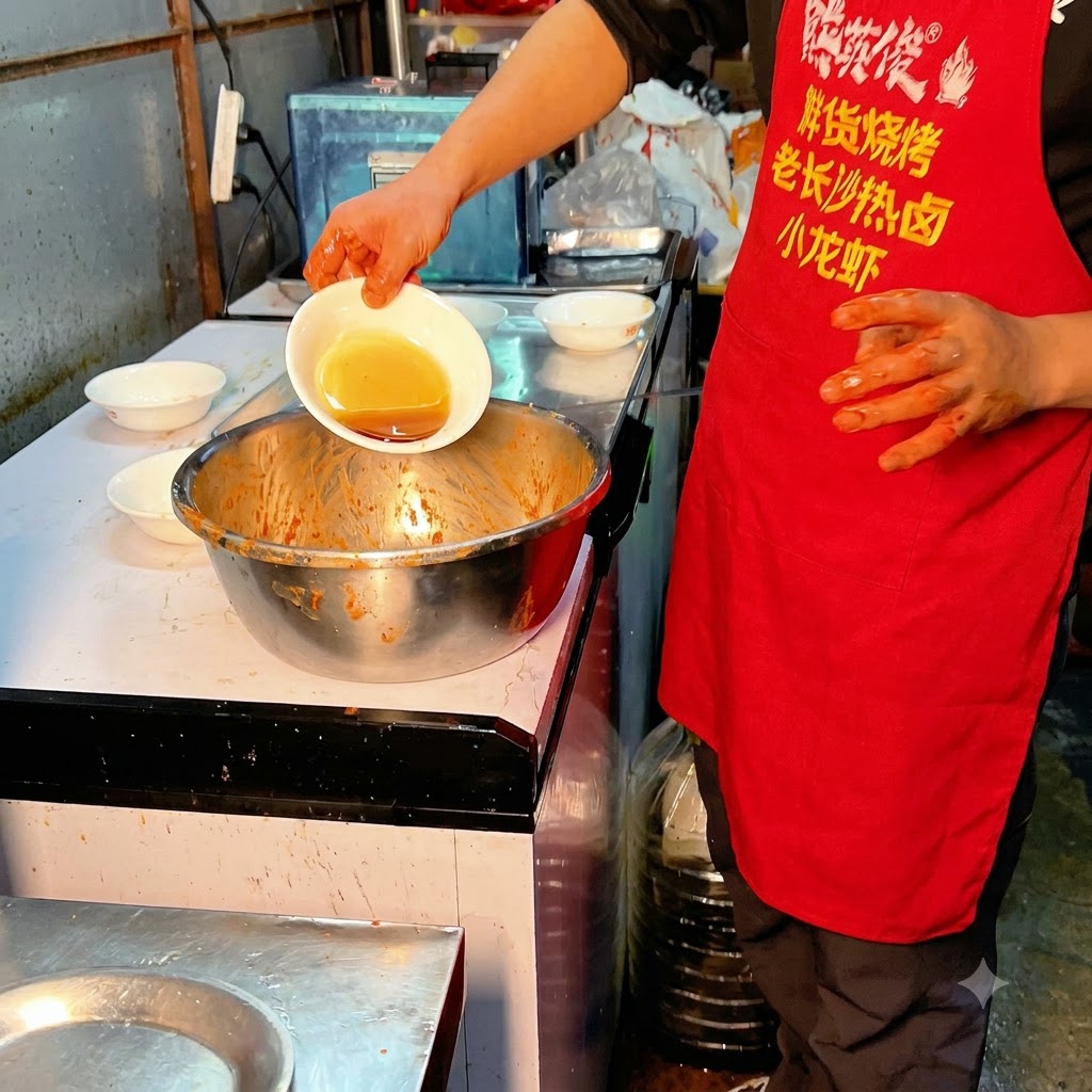 Cooking oil being poured from a small bowl into the seasoned pork ribs.