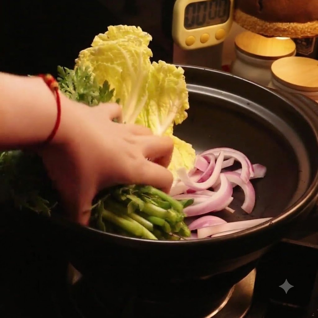 A hand placing fresh green vegetables into the pot beside the cabbage.