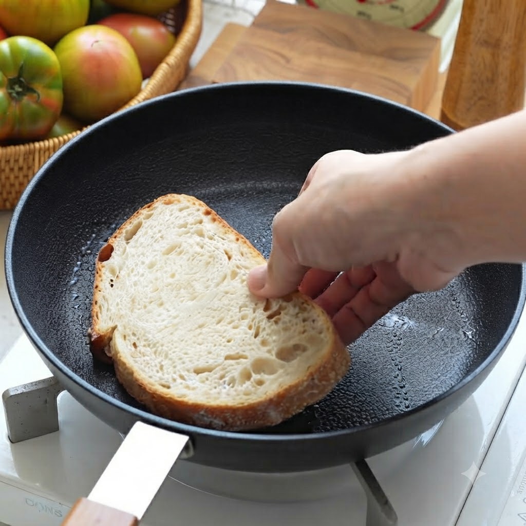 A slice of sourdough bread being placed into a black skillet to fry.