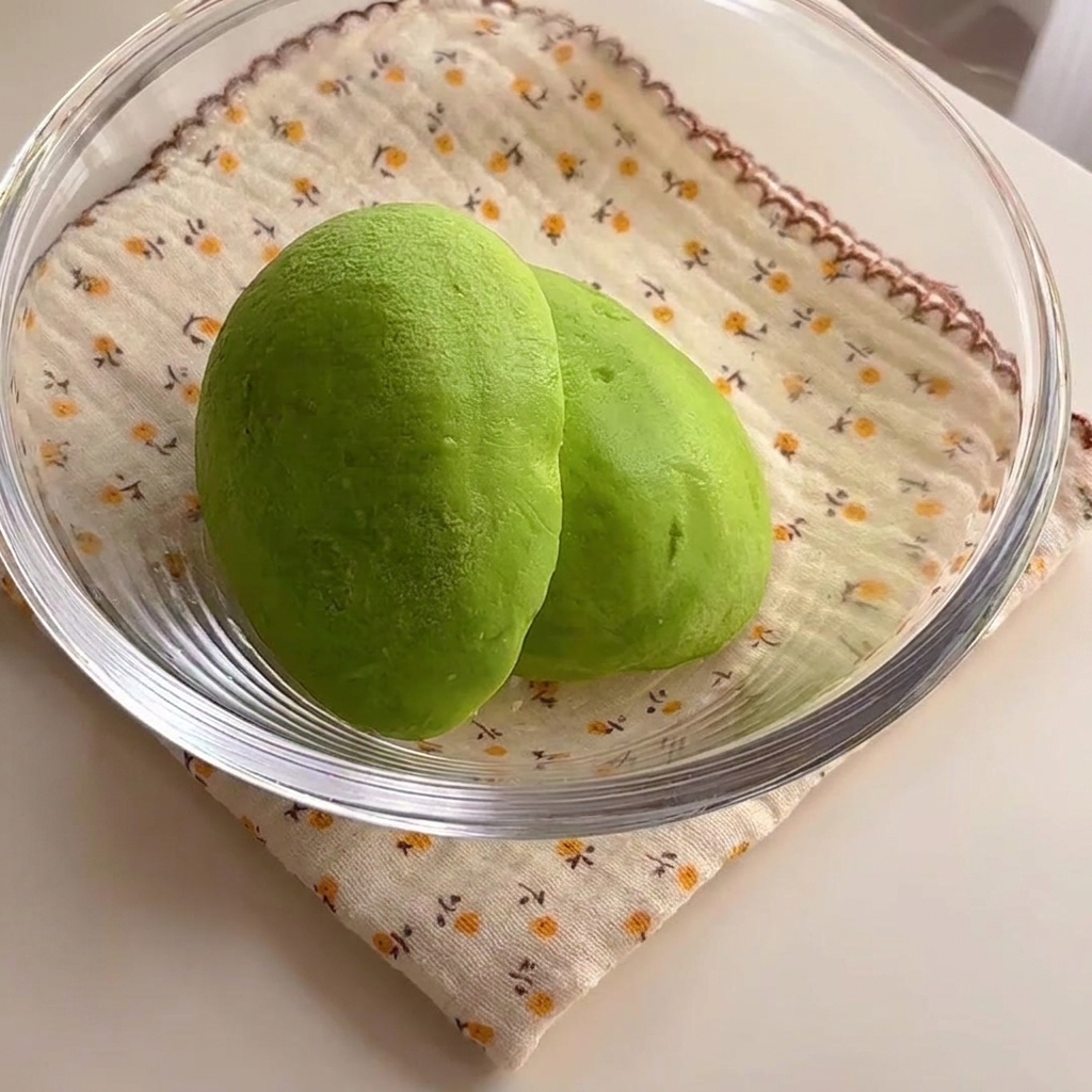Two vibrant green avocado halves sitting inside a glass bowl.