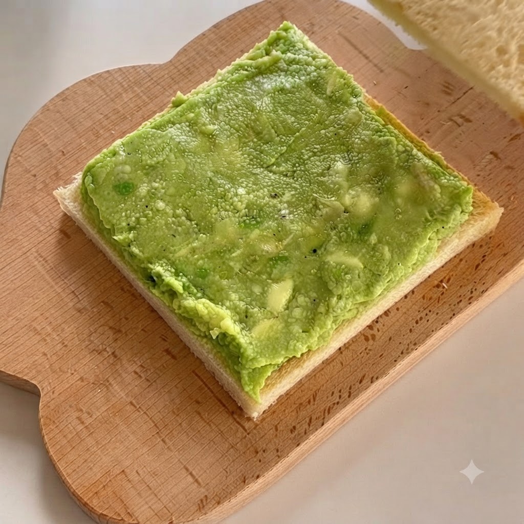 A second slice of white bread being placed directly on top of the layered avocado paste.
