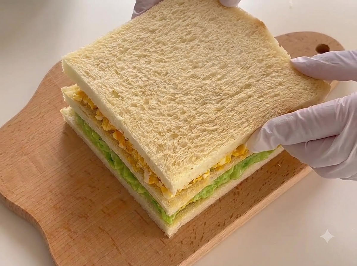 The fully assembled three-layer sandwich resting on a cutting board, ready for slicing.