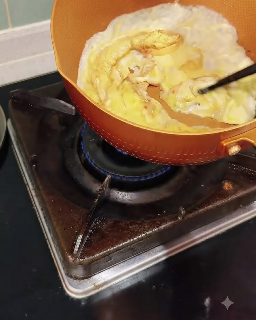 Eggs cooking in a pan being gently pushed and scrambled with chopsticks.