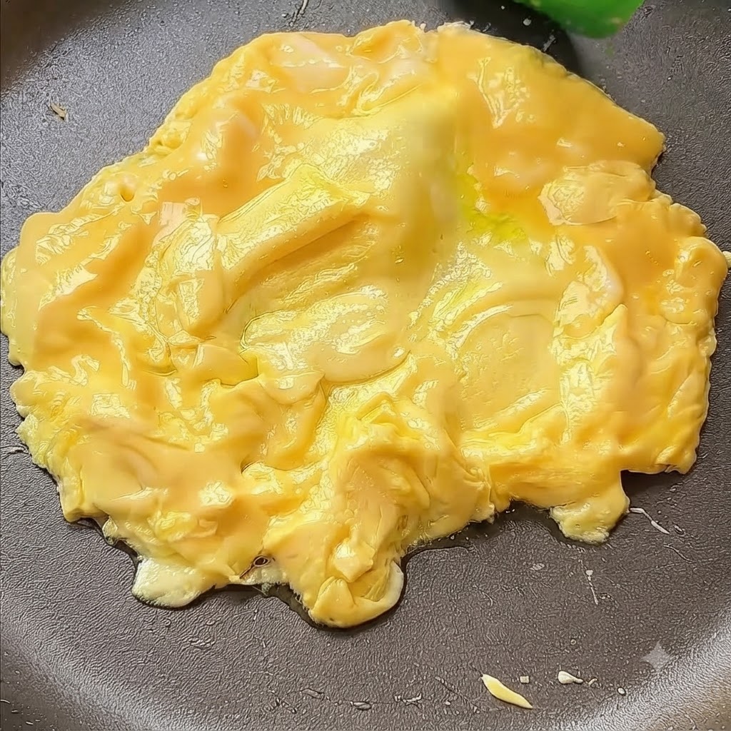 Eggs being pushed into the center of a pan with a spatula.